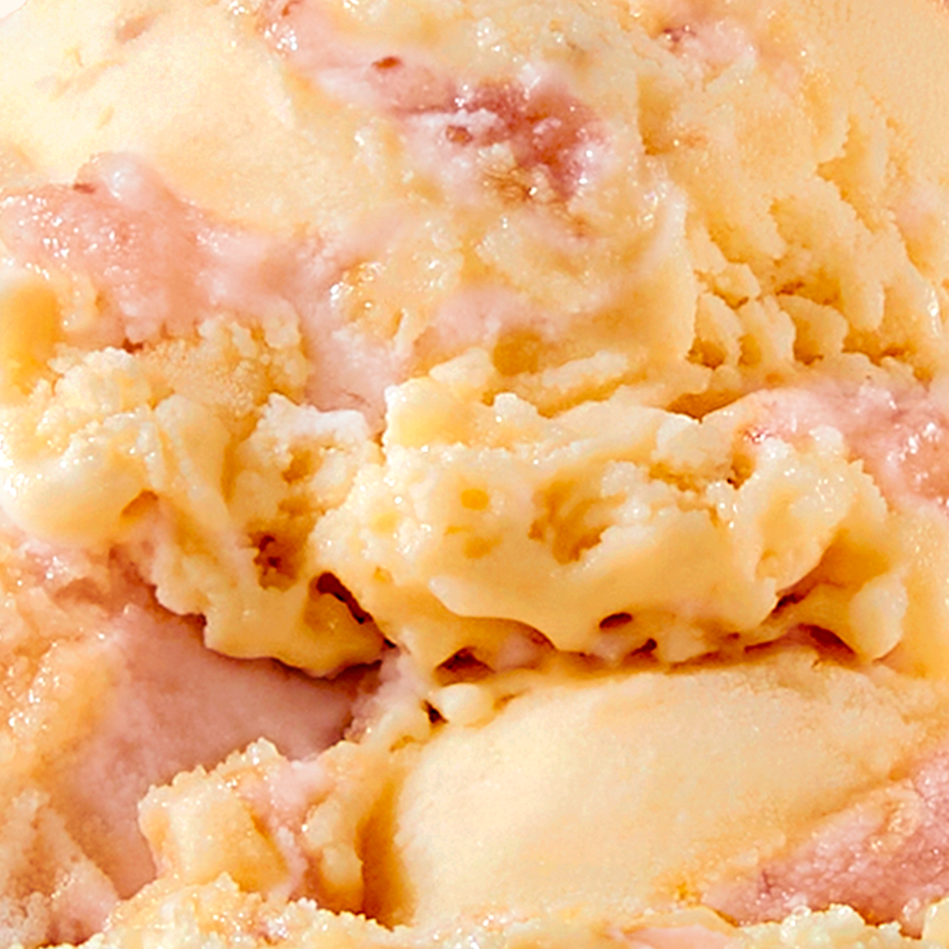 Close-up of scooped N!CK'S Mango Strawberry light ice cream in a bowl, showing the yellow mango base with visible red strawberry pieces.