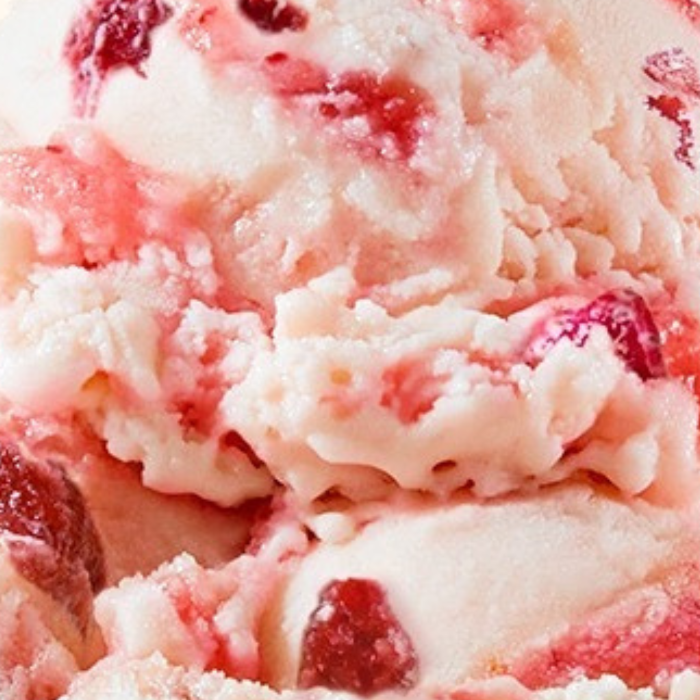 Extreme close-up texture shot of N!CK'S Strawberry Swirl light ice cream, showing pink and white swirls with visible chunks of real strawberry pieces.